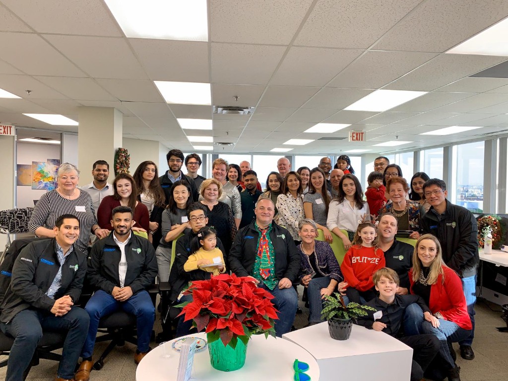 SmartONE team gathered in the office around a holiday poinsettia, about 40 people.